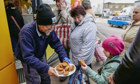 Fuminori Tsuchiko, 75-year-old humanitarian volunteer from Japan, treats a girl with cookies outside his cafe in Kharkiv.