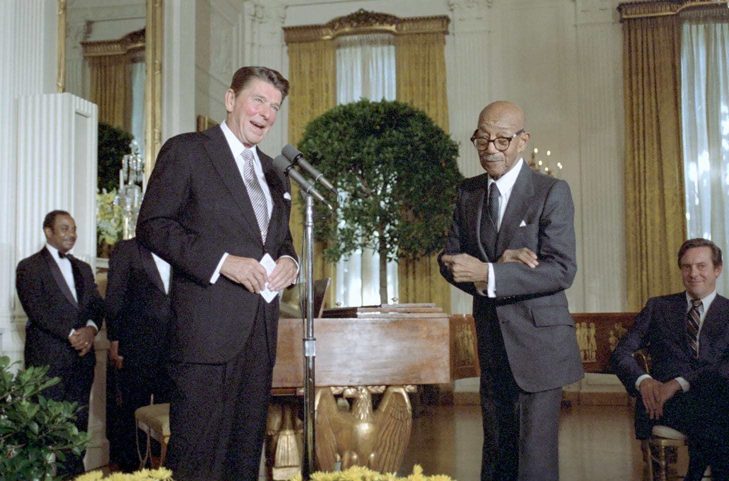 Photograph of Eubie Blake, an older African American man, posing at a podium beside President Ronald Reagan.