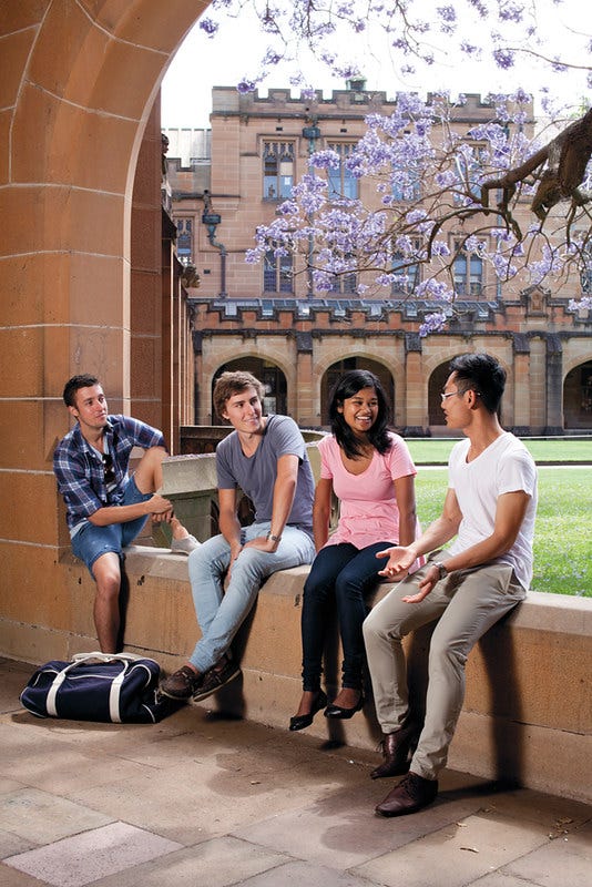 Four university students sitting and chatting while on campus.