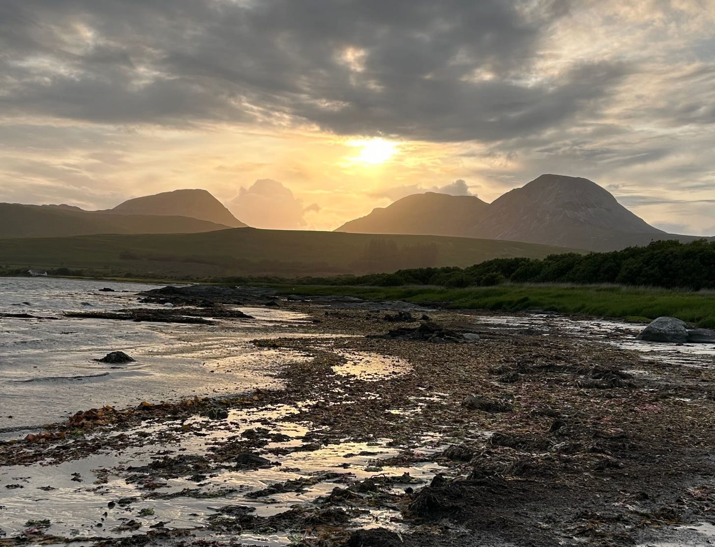 Three mountains silhouetted against a sunset