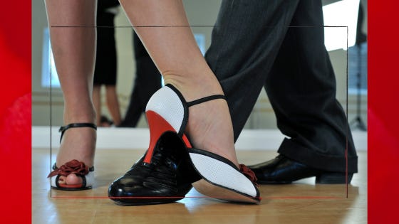 A white-and-red high heel crosses with a debonaire black dance shoe.
