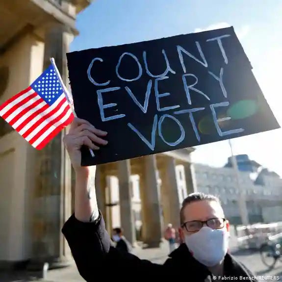 A demonstrator holds a placard and a U.S. flag during the 'Count the Votes! Rally for Fair Elections in the USA'