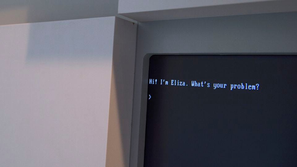 A computer with the words Hi! I'm Eliza. What's your problem?