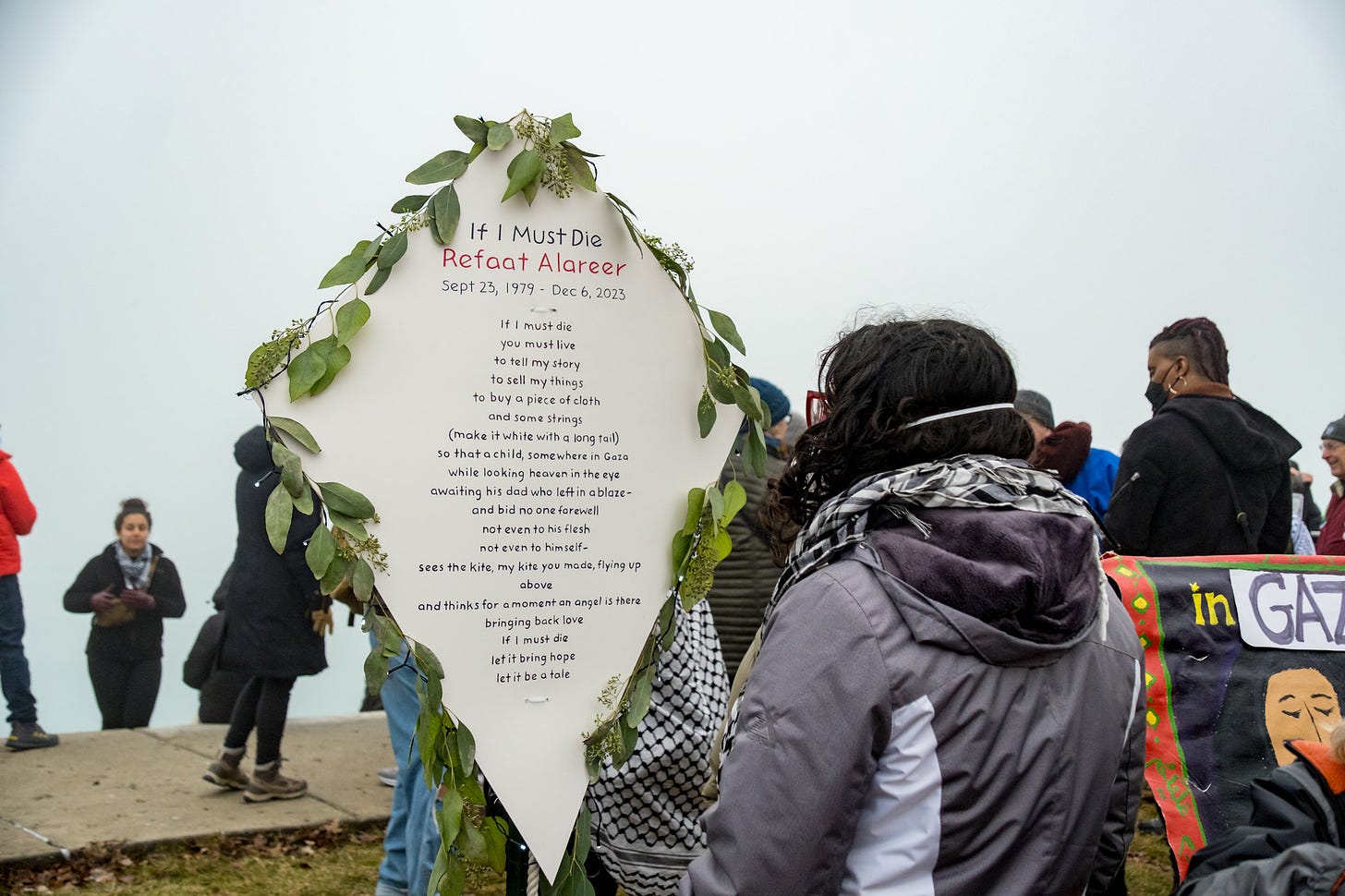 A protester looks at a decorative kite bearing the words of Refaat Alareer's poem "If I Must Die."