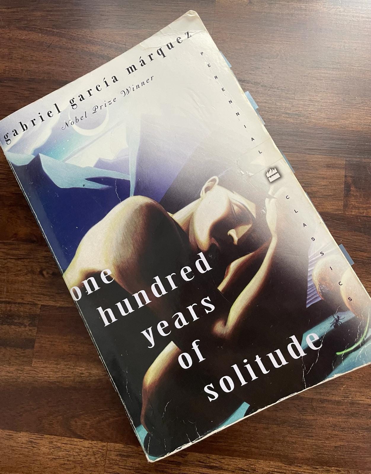 Copy of One Hundred Years of Solitude by Gabriel García Márquez sits on wood desk surface