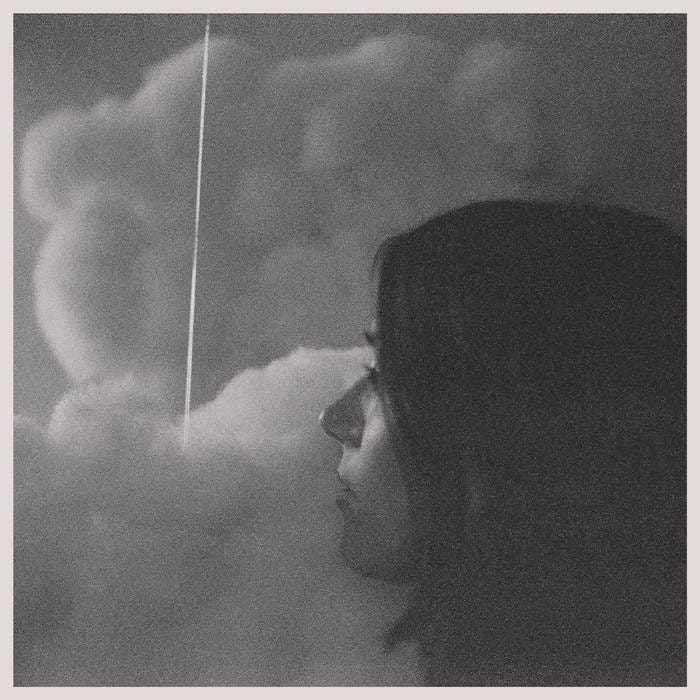 Romantic Piano album cover: side view of a woman's face in front of a background of clouds. She has light skin and dark hair. 