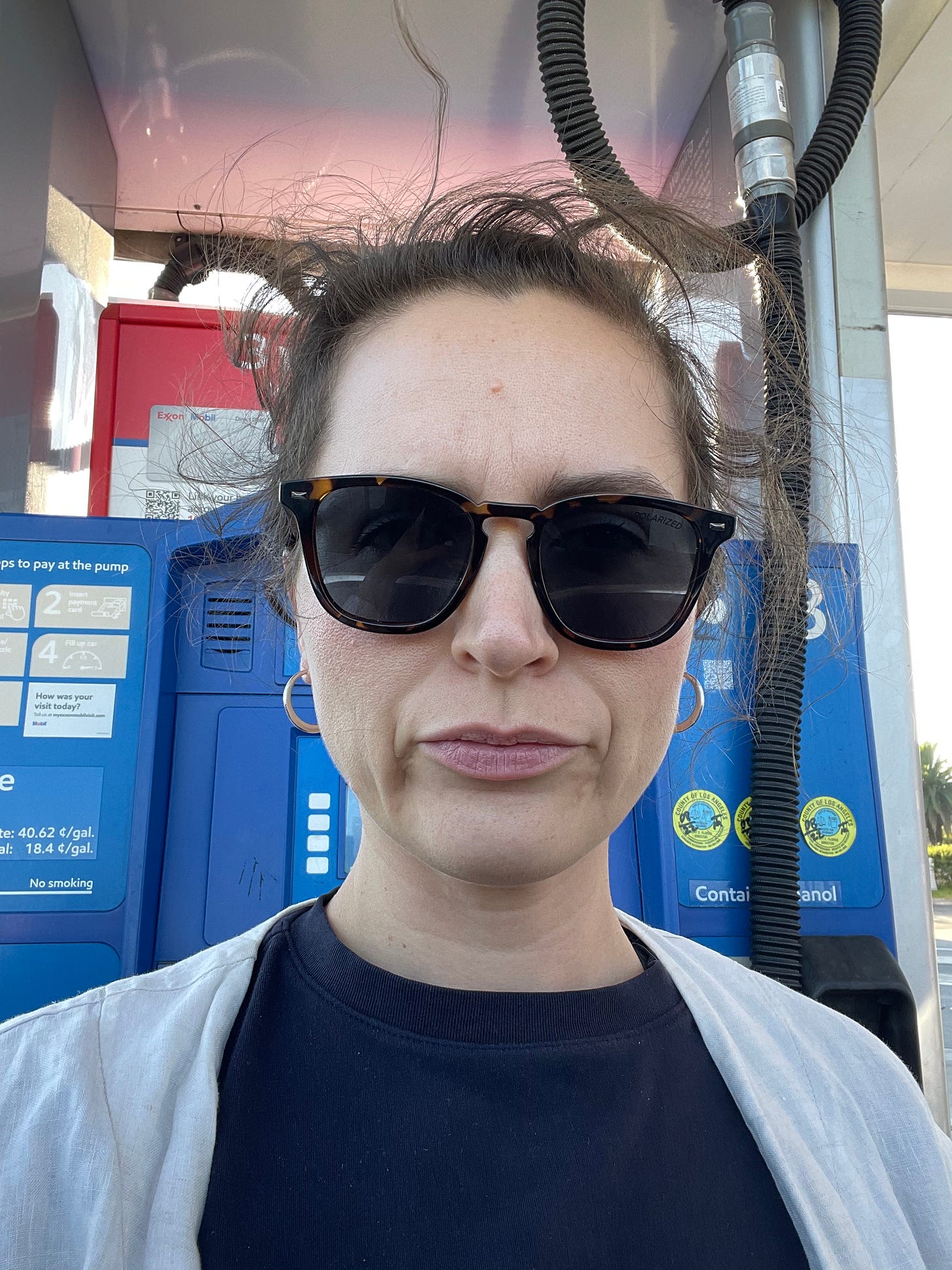 Woman in front of a gas station pump with very frizzy hair