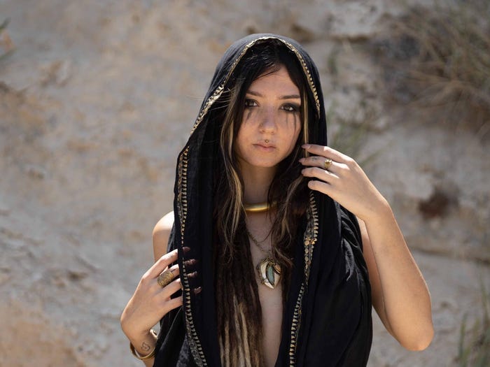 A woman with dreadlocks, dramatic makeup, and a piece of fabric draped over her head.