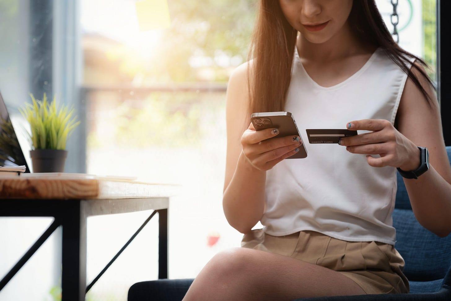 ~A woman tapping card details into her phone (Alamy/PA)