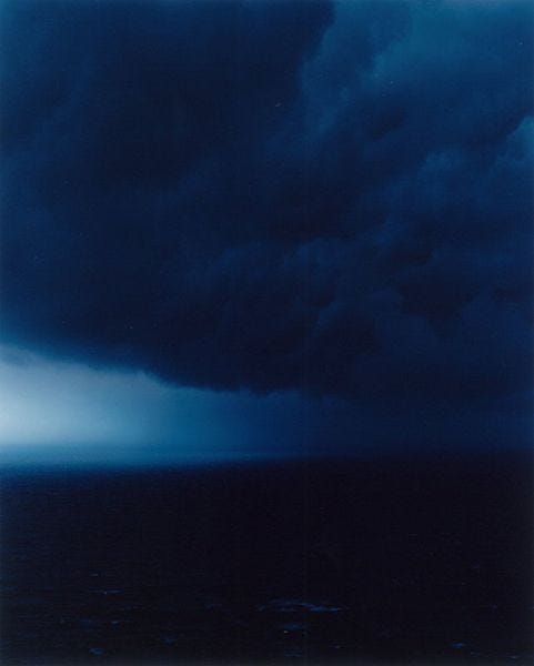 This may contain: the sky is dark and cloudy over the ocean