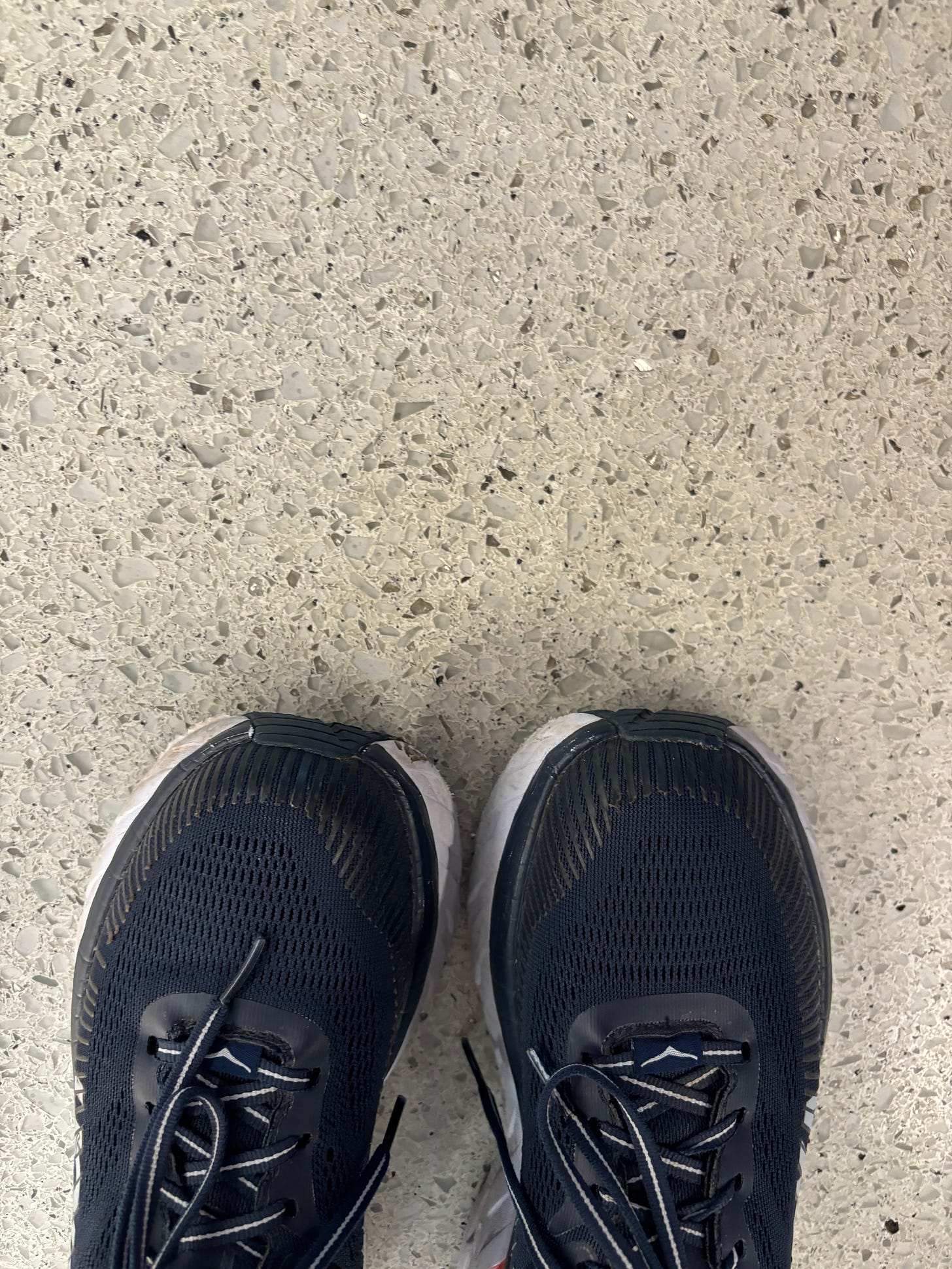 The author’s hoka sneakers side by side on her feet on a laminate floor