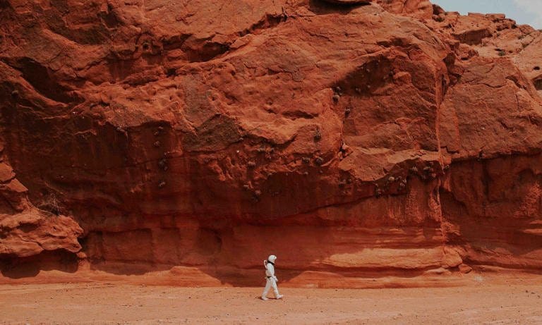 A lone traveler walks among red rocks