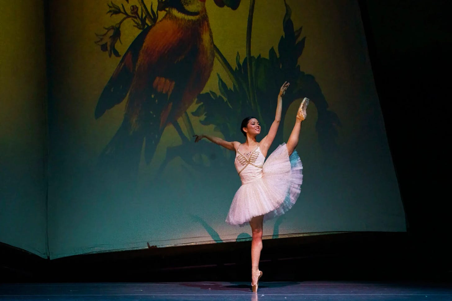 Mikaela Santos, a ballet dancer from the Philippines, wears a white tutu and does a développé à la seconde en pointe. She is dancing as Marie in Atlanta Ballet's The Nutcracker. 
