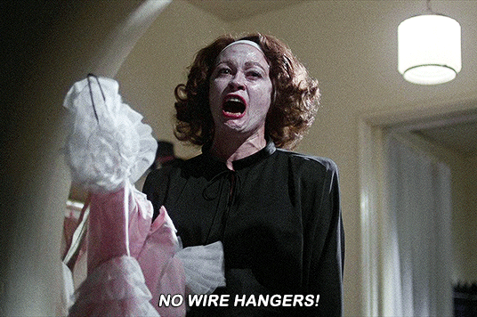 Gif of Joan Crawford from the film Mommie Dearest holding a dress and screaming "NO WIRE HANGERS." 
