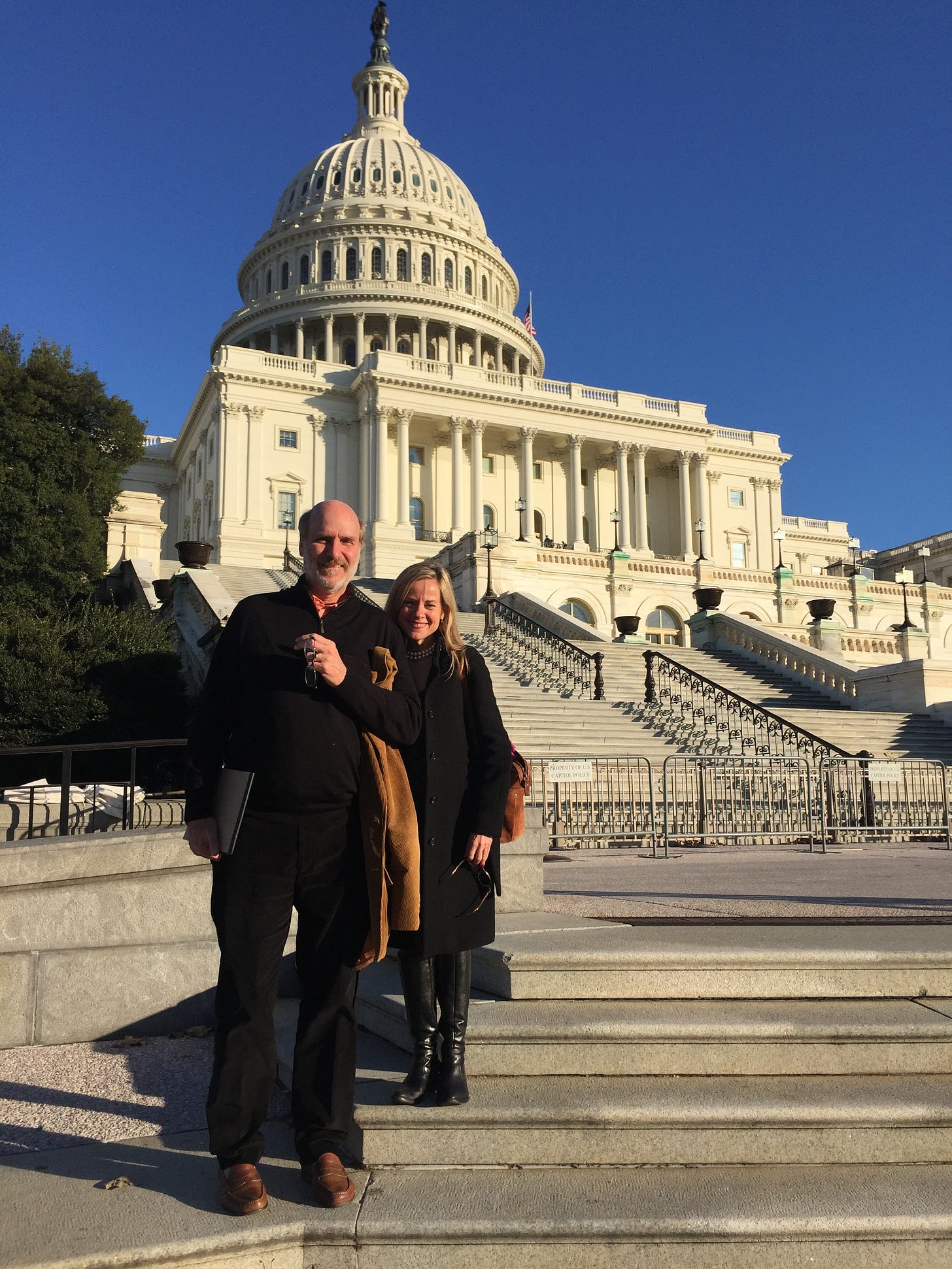 A man and woman stand on the steps of the U.S. Capitol