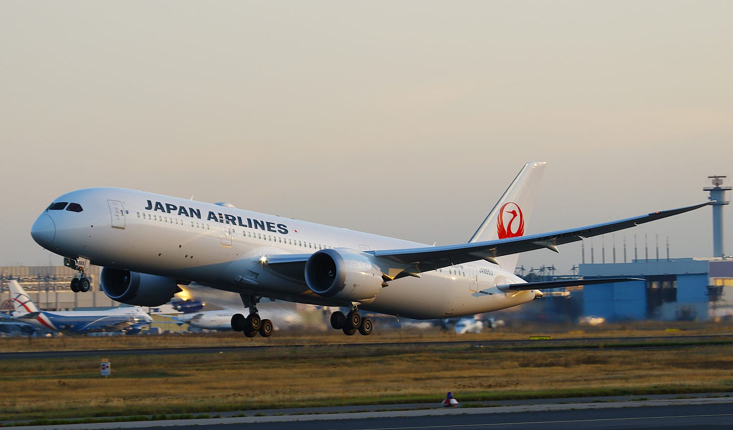 A Japan Airlines Boeing 787 Dreamliner taking off from an airport runway at dusk.