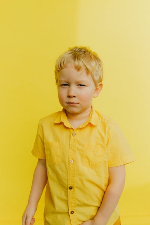Free Boy in Yellow Button Up Shirt Standing Near Wall Stock Photo