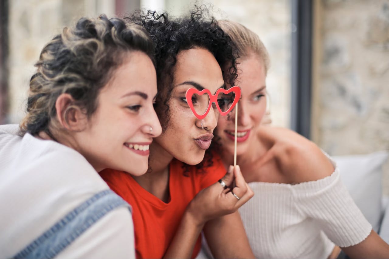 Three female friends put their heads together and smile for a selfie.