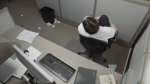 A man in an office cubicle spins in his chair