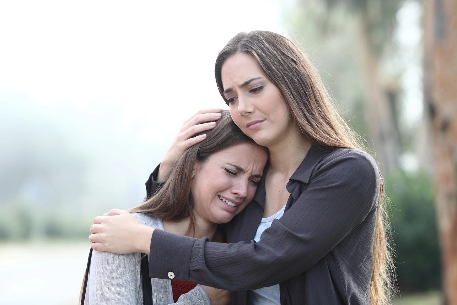 Middle aged woman holding a 20-something girl who is crying