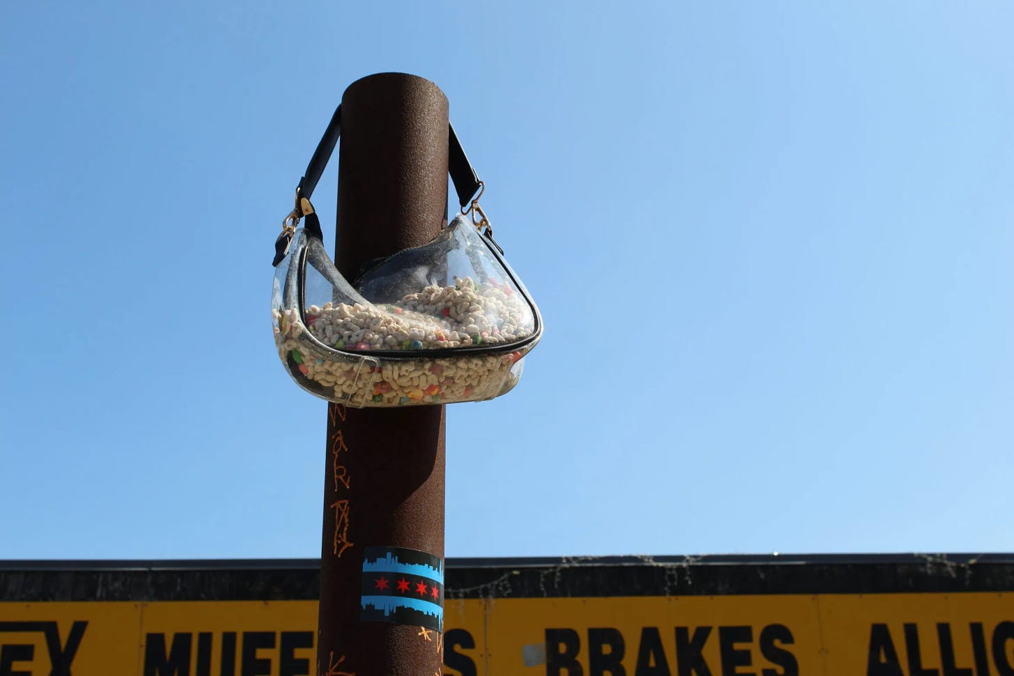 A clear shoulder bag with a black strap hangs over a large metal pole. The purse is full of dry Lucky Charms