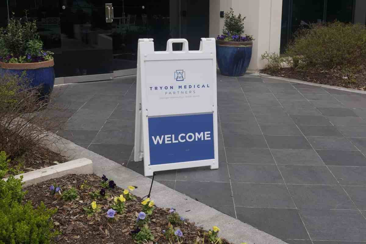 A pop up plastic sign on a sidewalk which reads "welcome"