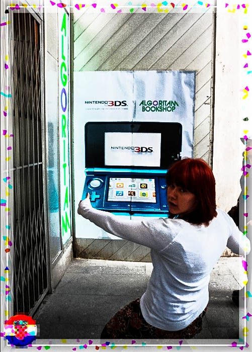 Foto van Amy die voor een poster van Nintendo 3DS staat, zo gepositioneerd dat het lijkt alsof ze op een gigantische 3DS speelt, met een fotokader van Kroatië.