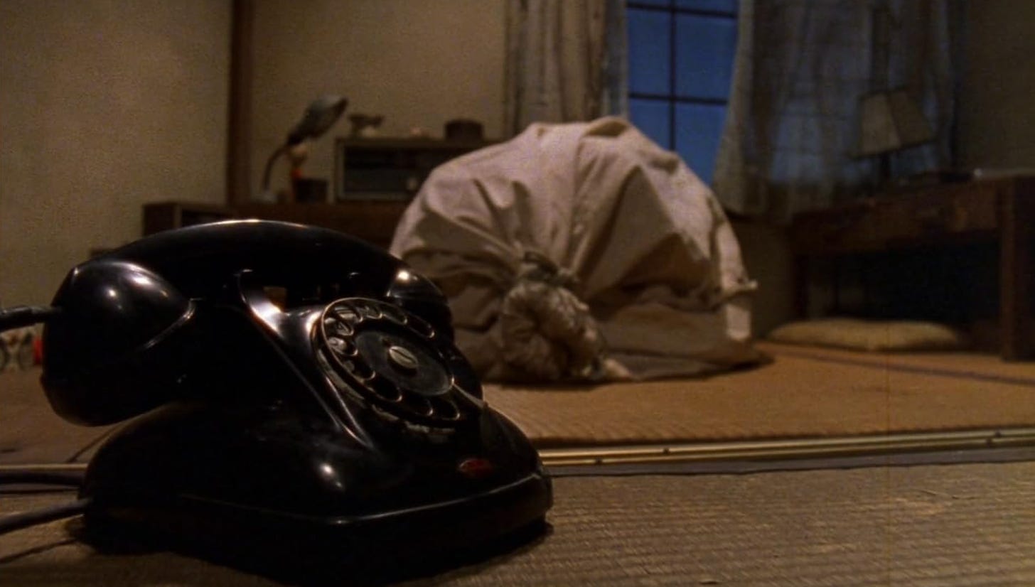 A man bound in a bag next to a black rotary phone in Miike's "Audition" (1999)