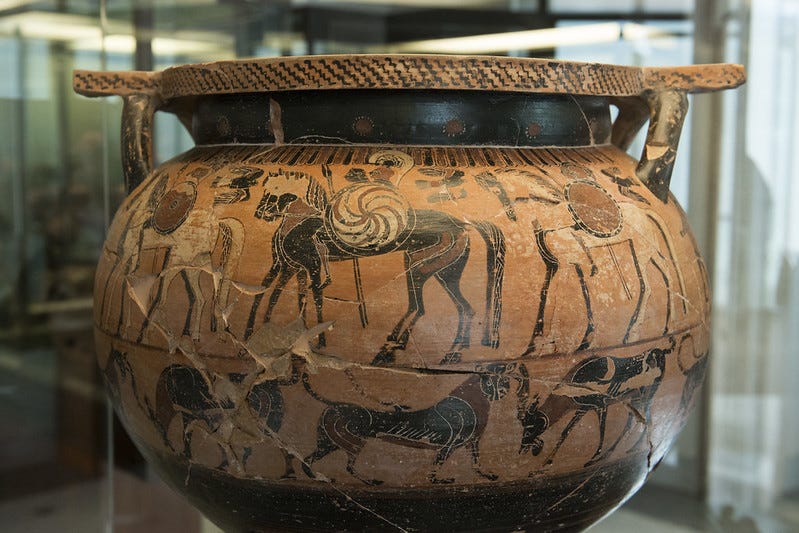 Color photograph of a black figure vase with horses and warriors proceeding right to left