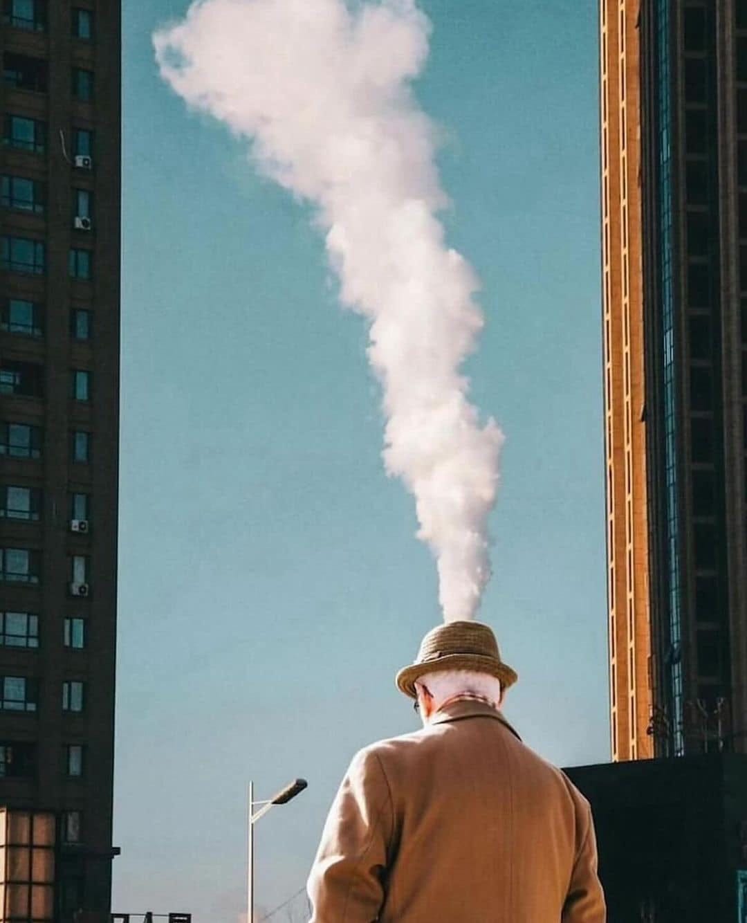 May be an image of 1 person, overcoat, street and skyscraper