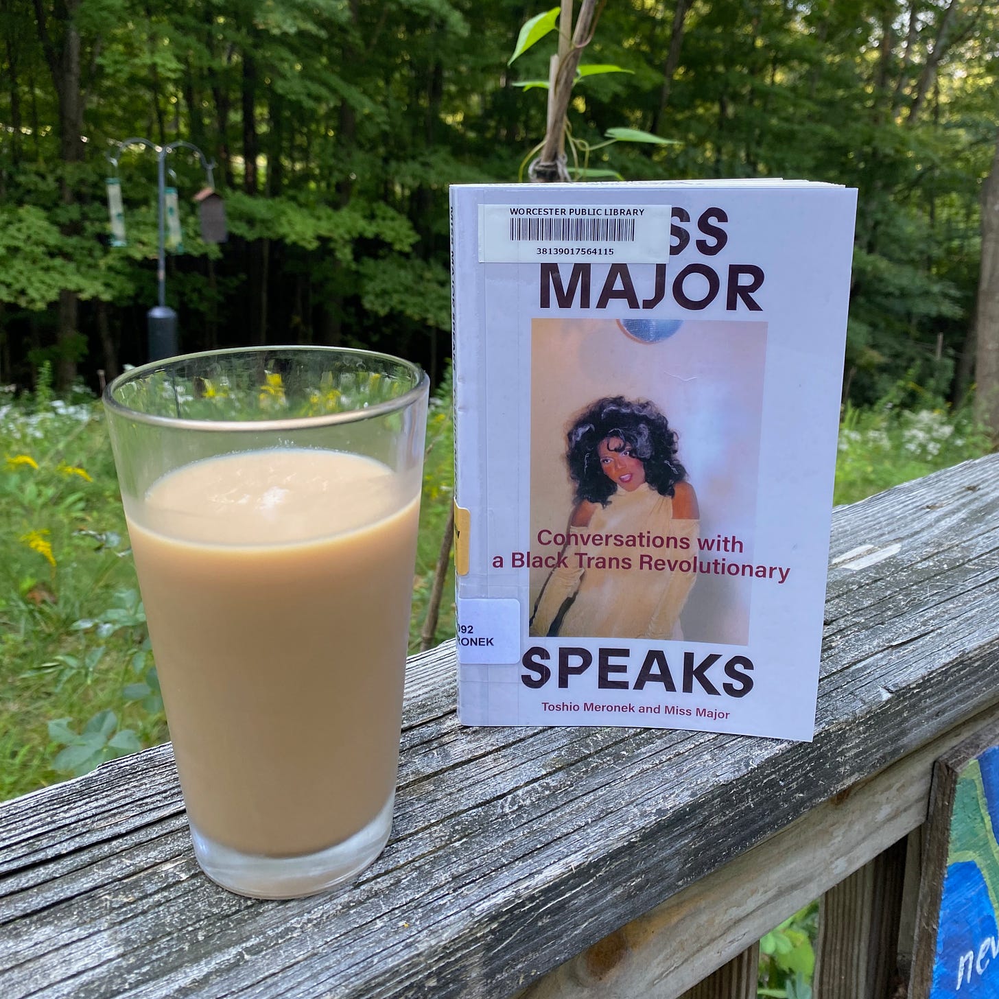 Miss Major speaks standing upright on a porch railing next to a glass of iced tea.