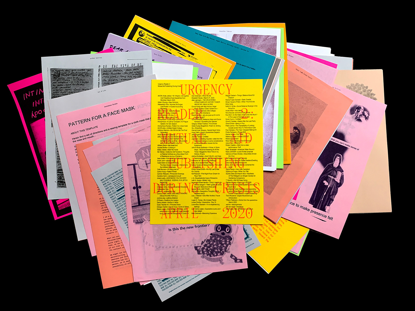 An array of multicolored printed pages with text and images are spread out on a black background. Text on the top page reads URGENCY READER 2: MUTUAL AID PUBLISHING DURING CRISIS. 