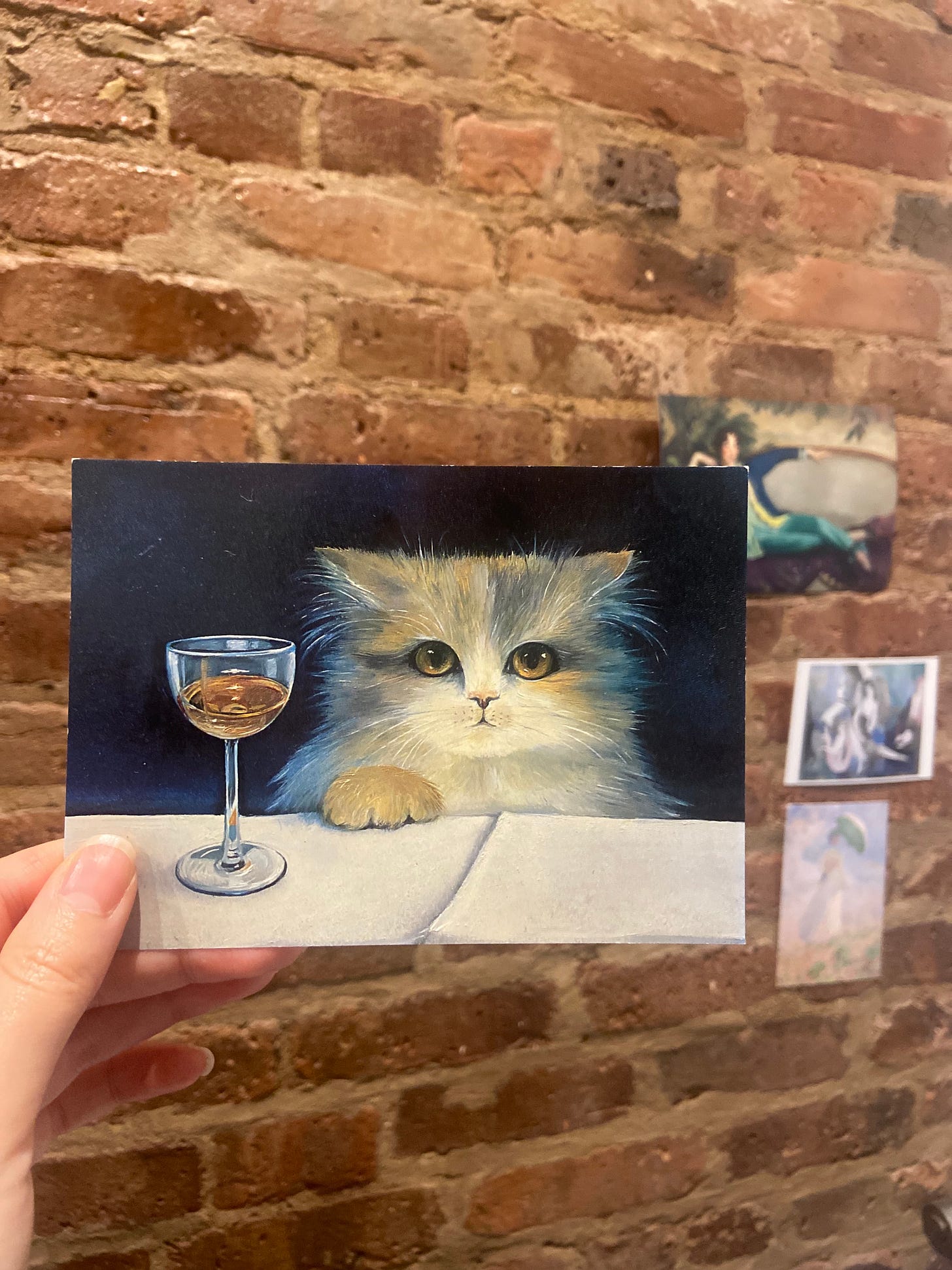 Postcard of a fluffy cat with a glass of brandy.