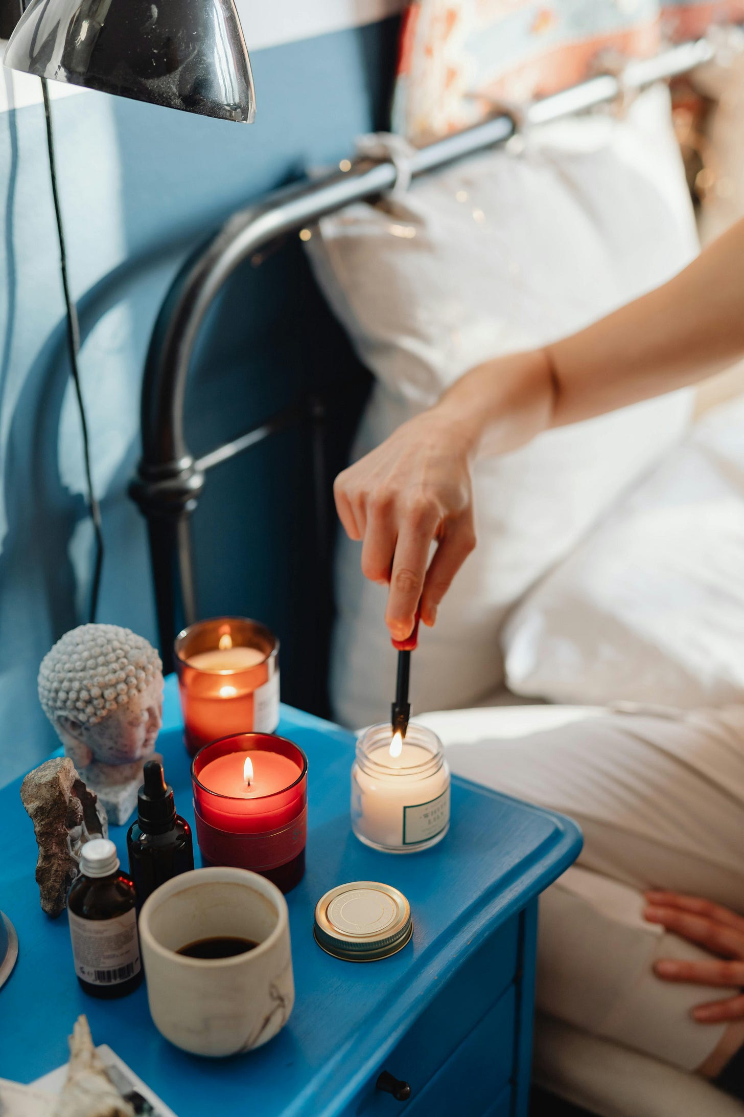 A person's hand lighting a candle at bedside
