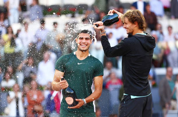 Alexander Zverev of Germany pours champagne over and congratulates Carlos Alcaraz Garfia of Spain after the men's singles final match at La Caja...