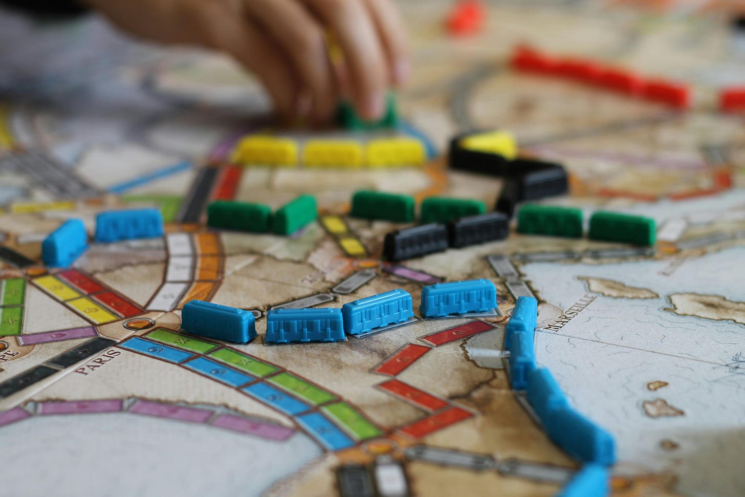 A photo of a board game with multicoloured train tracks and little train counters