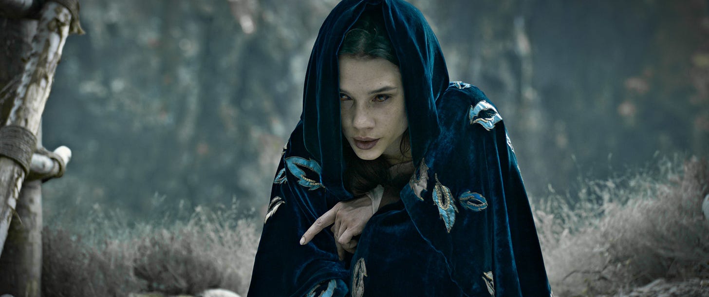 woman with blue cloak in woods looking spooky