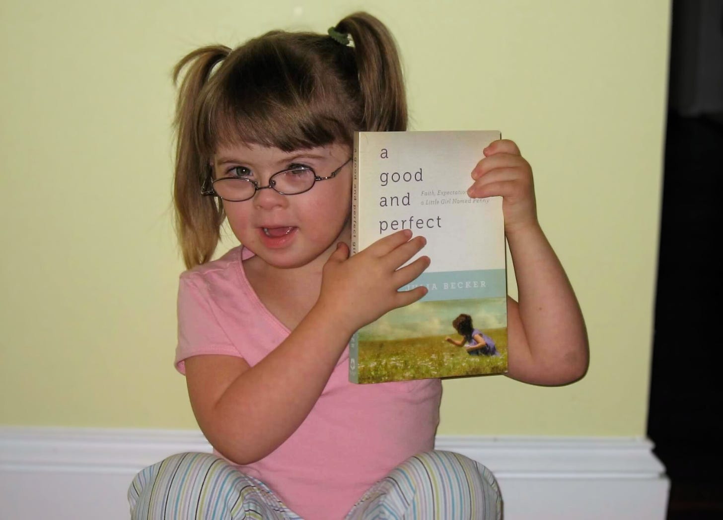 photo of 5-year-old Penny holding a copy of a Good and Perfect Gift