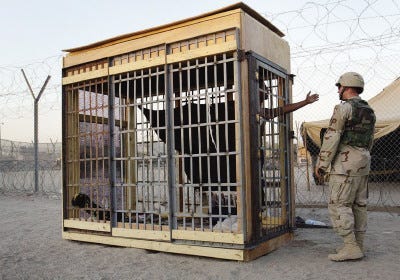 John Moore/Associated Press file photoA detainee in an outdoor solitary confinement cell talks with a military policeman at the Abu Ghraib prison on the outskirts of Baghdad, Iraq in this 2004 file photo. When the Americans formally turned over Abu Ghraib prison to Iraqi control on Sept. 2, this year, it was empty, but its 3,000 prisoners remained in U.S. custody, shifted to Camp Cropper.