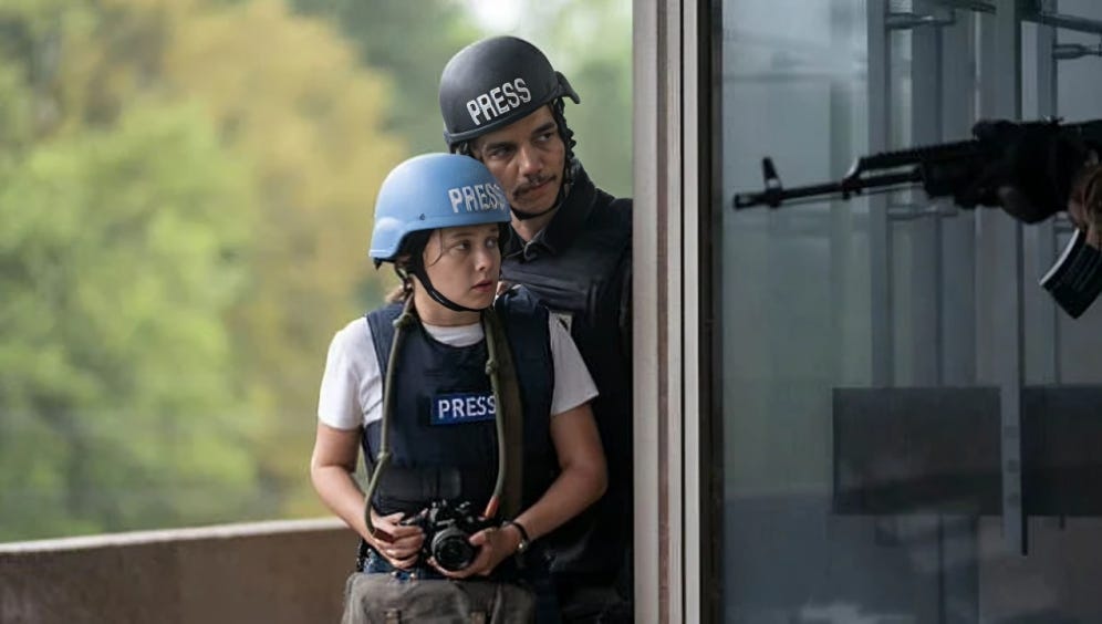 A young press reporter and an older male colleague peer cautiously around a corner with a machine gun positioned in the foreground.