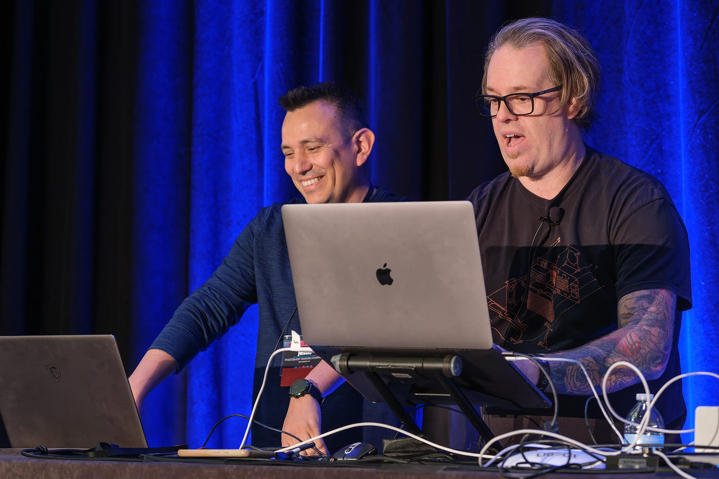 Two men, Jesús Ramirez (left) and Mark Heaps (right) give a presentation using their laptops at CreativePro Week 2022.