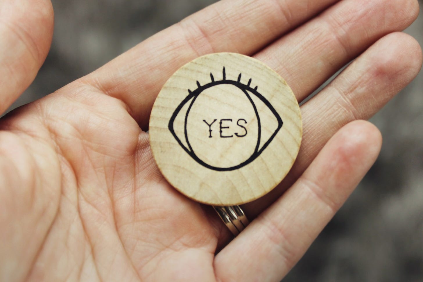 A hand holding a piece of wood with the word yes on it