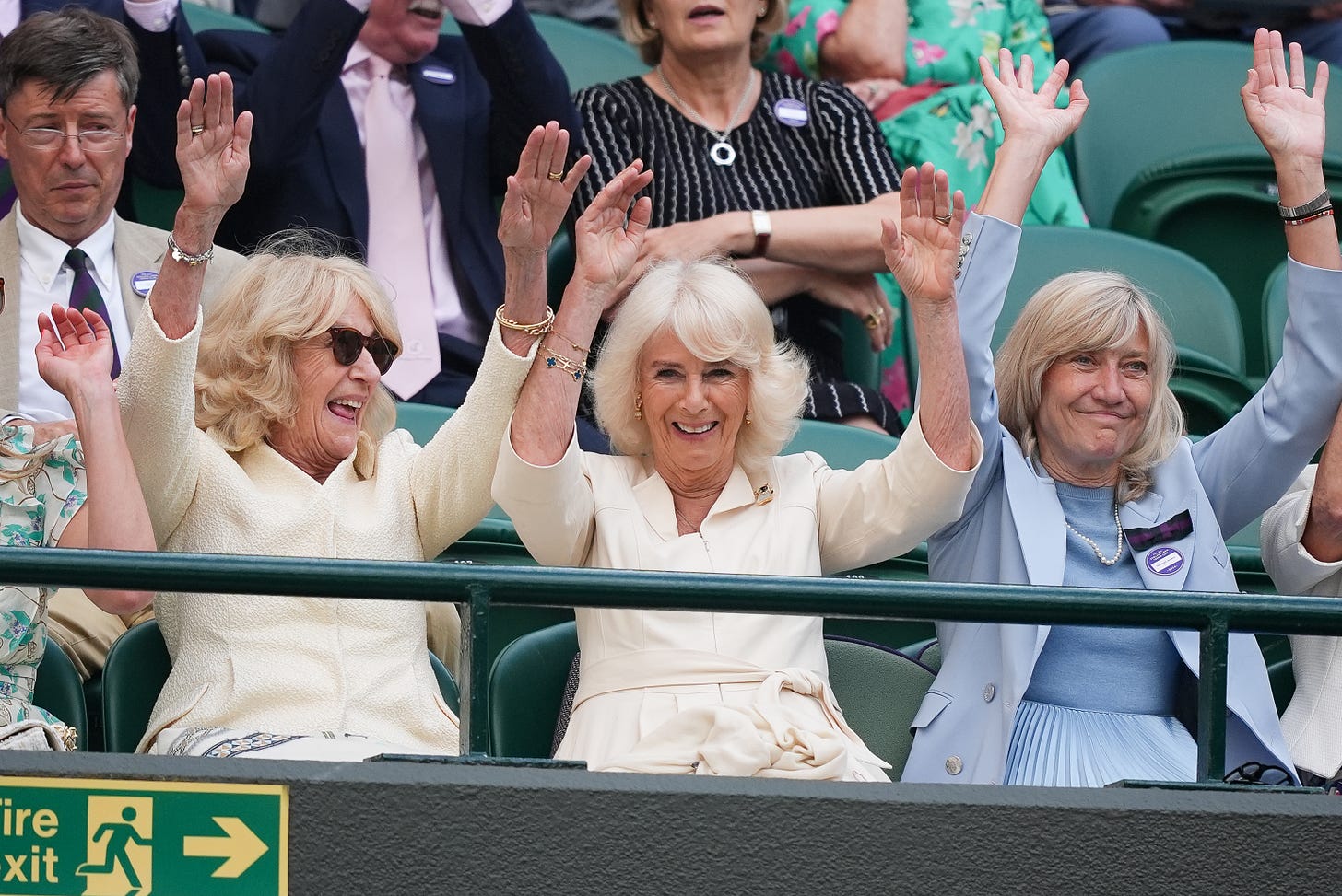 Queen Camilla raising her hands in the air in Wimbledon crowd