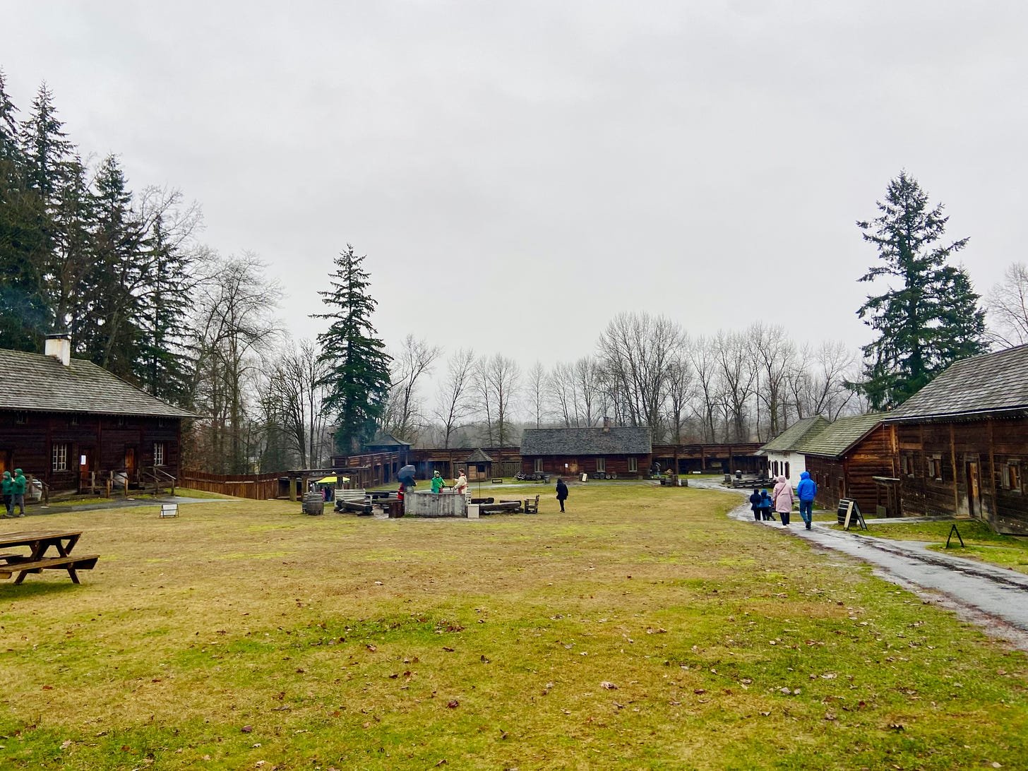 large grassy area with fire pit surrounded by colonial buildings at Fort Langley