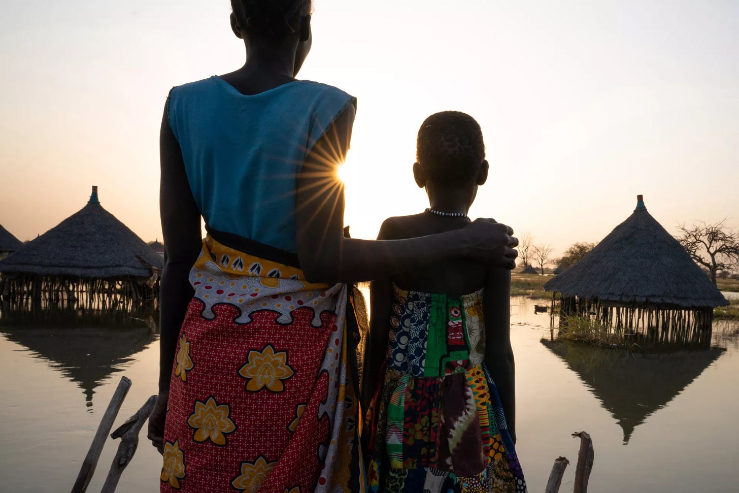 A mother and daughter look out over submerged houses 