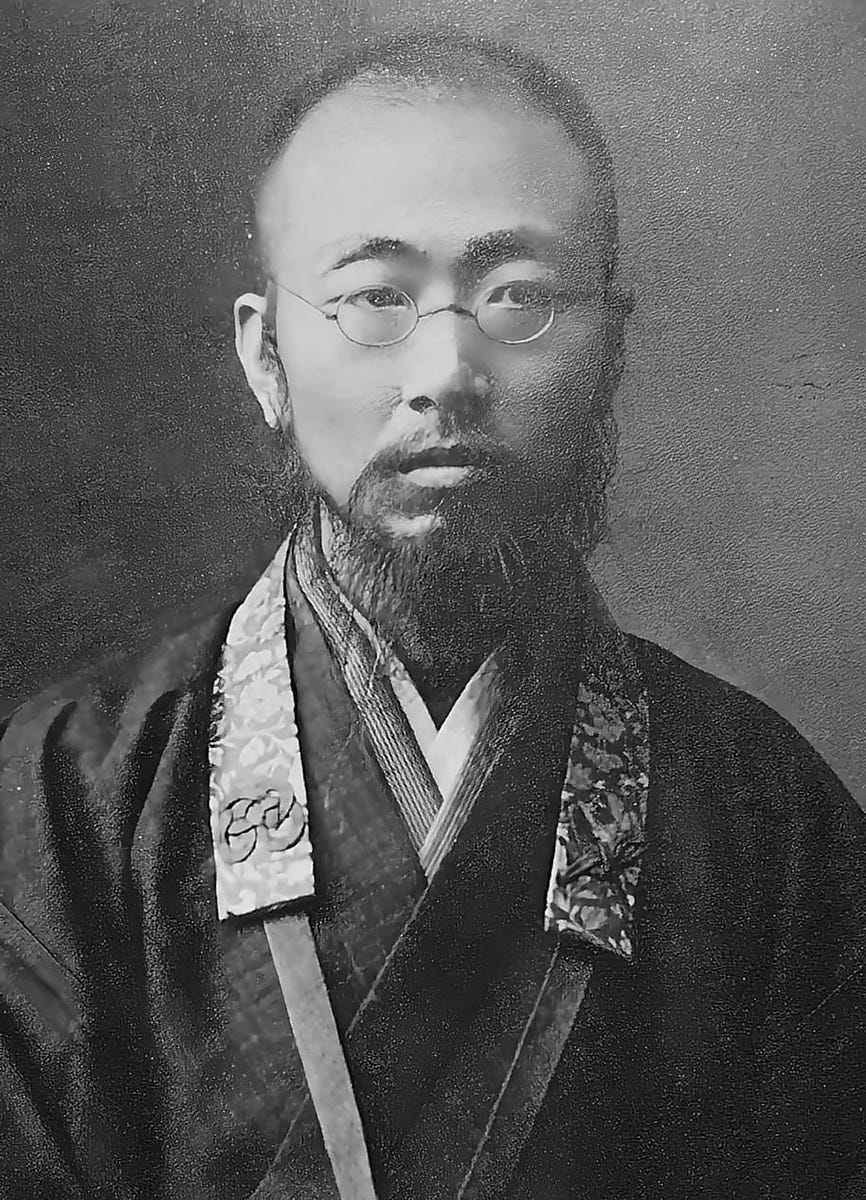 Old black and white photo of a young Japanese man with glasses and a beard