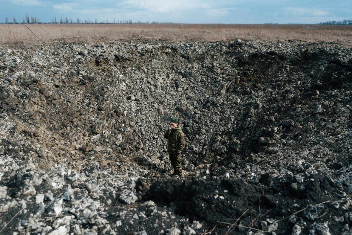A Ukrainian soldier assesses the crater from a glider bomb explosion in Donetsk