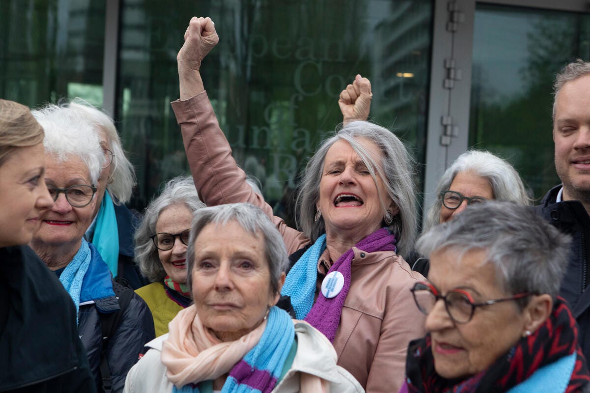 A group of senior Swiss ladies in scarves celebrate their win at the European Court of Human Rights.