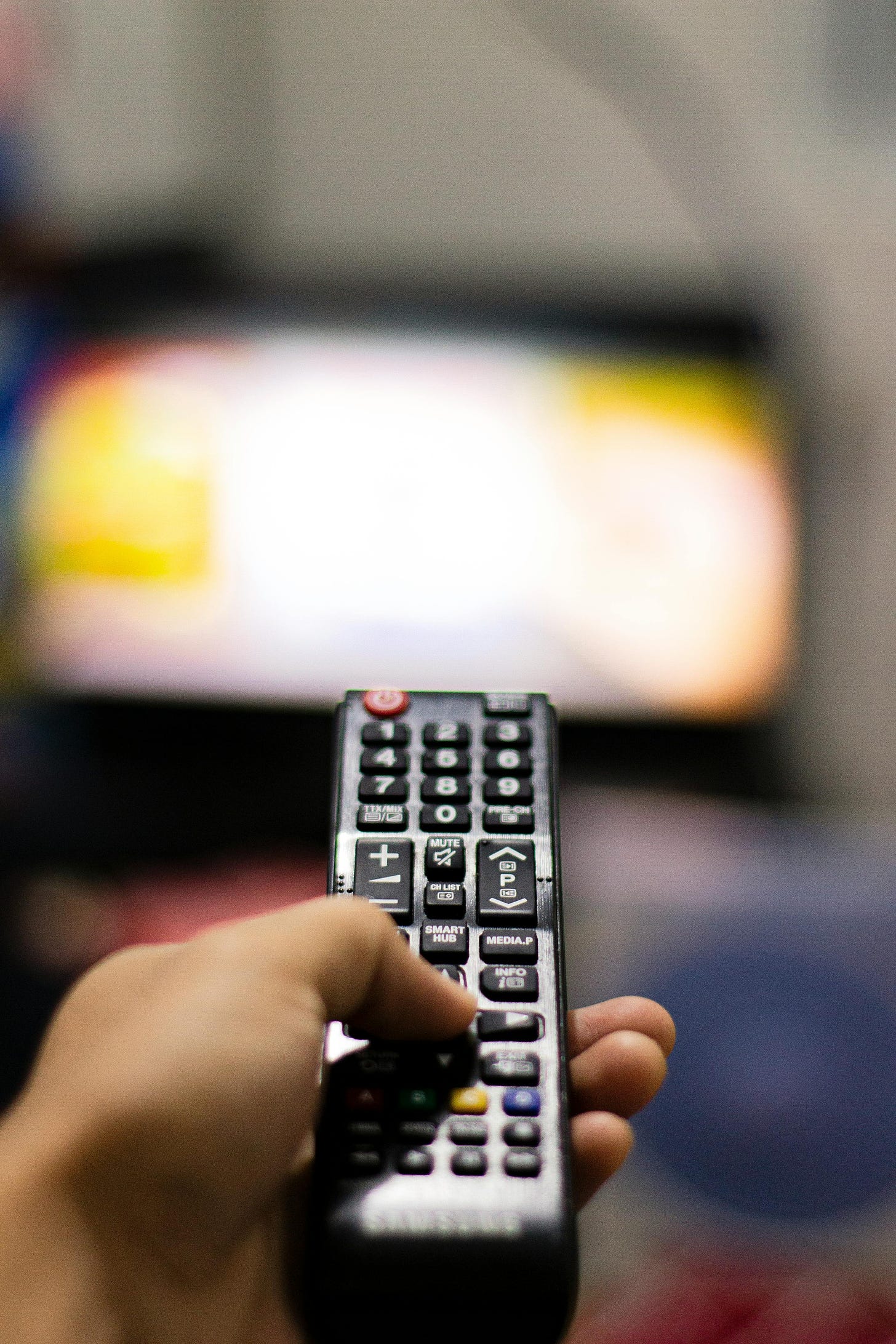 a remote control pointing at an out of focus TV set