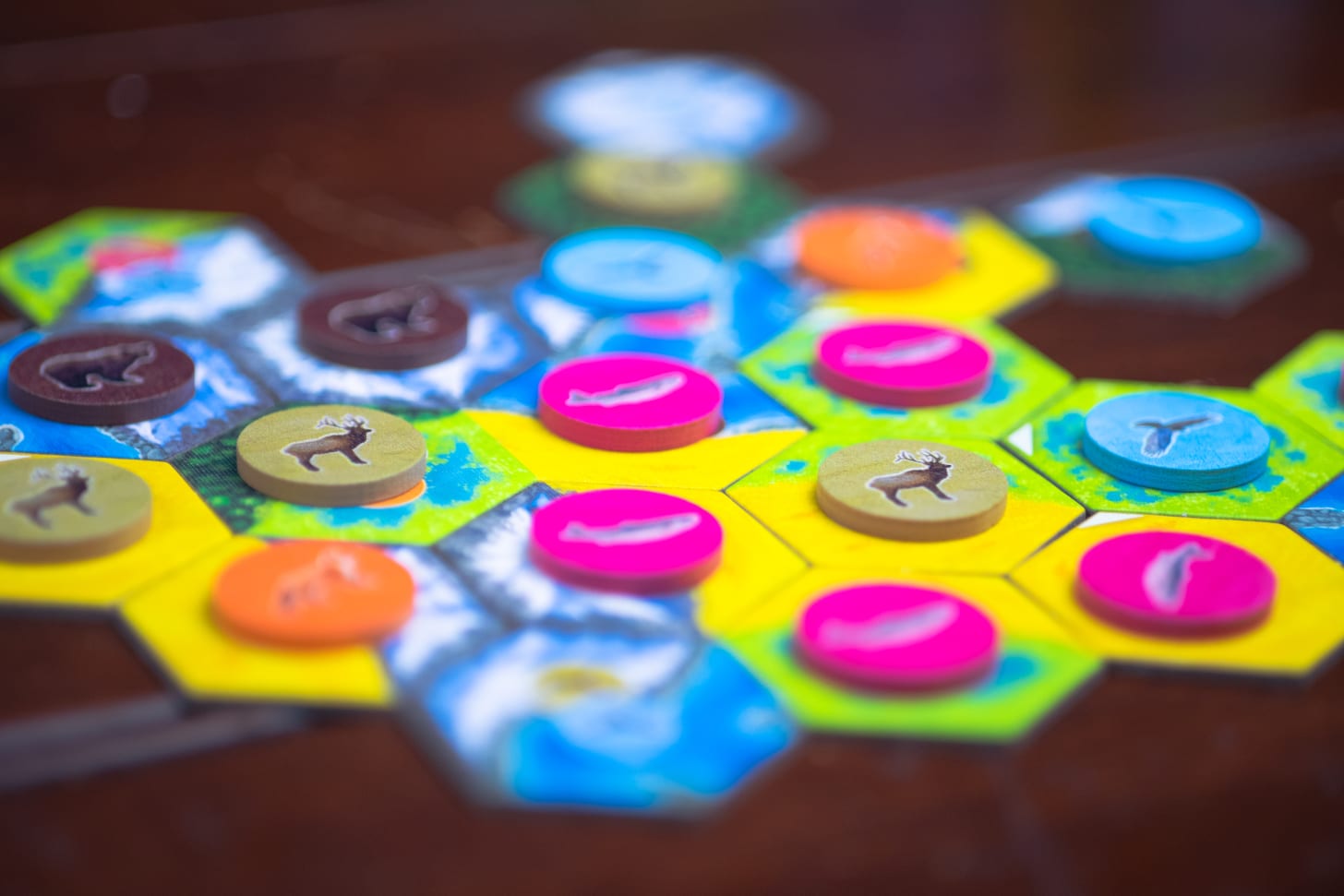 Tiles and tokens from the game Cascadia during play on a table.